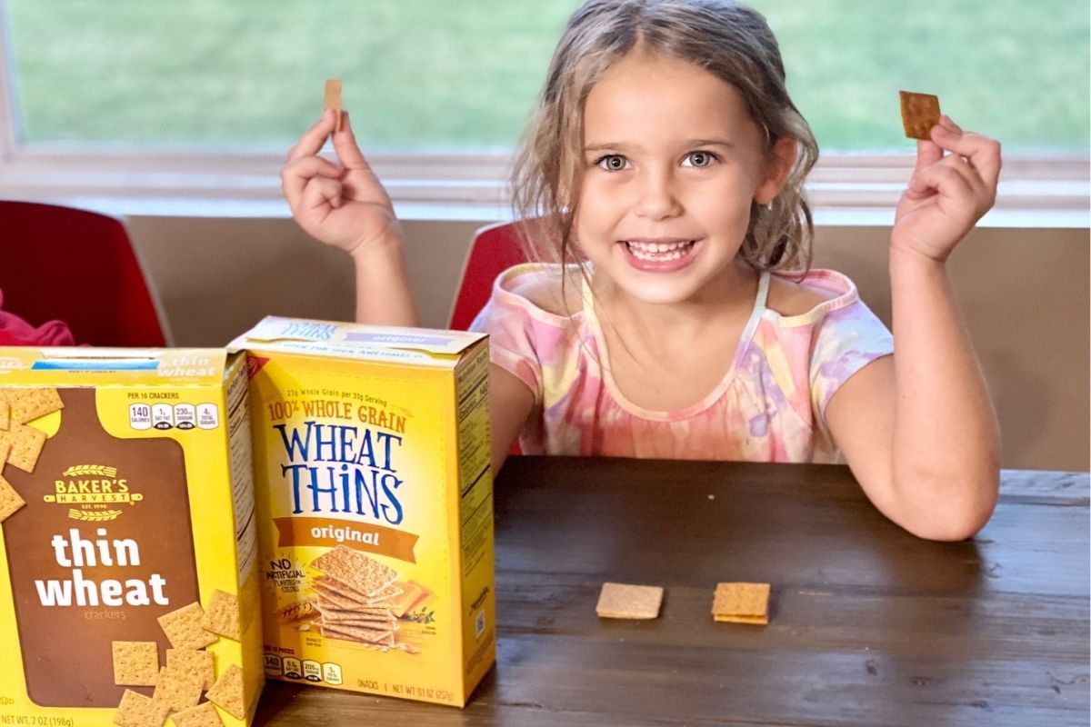 A little girl at a table with crackers in hands