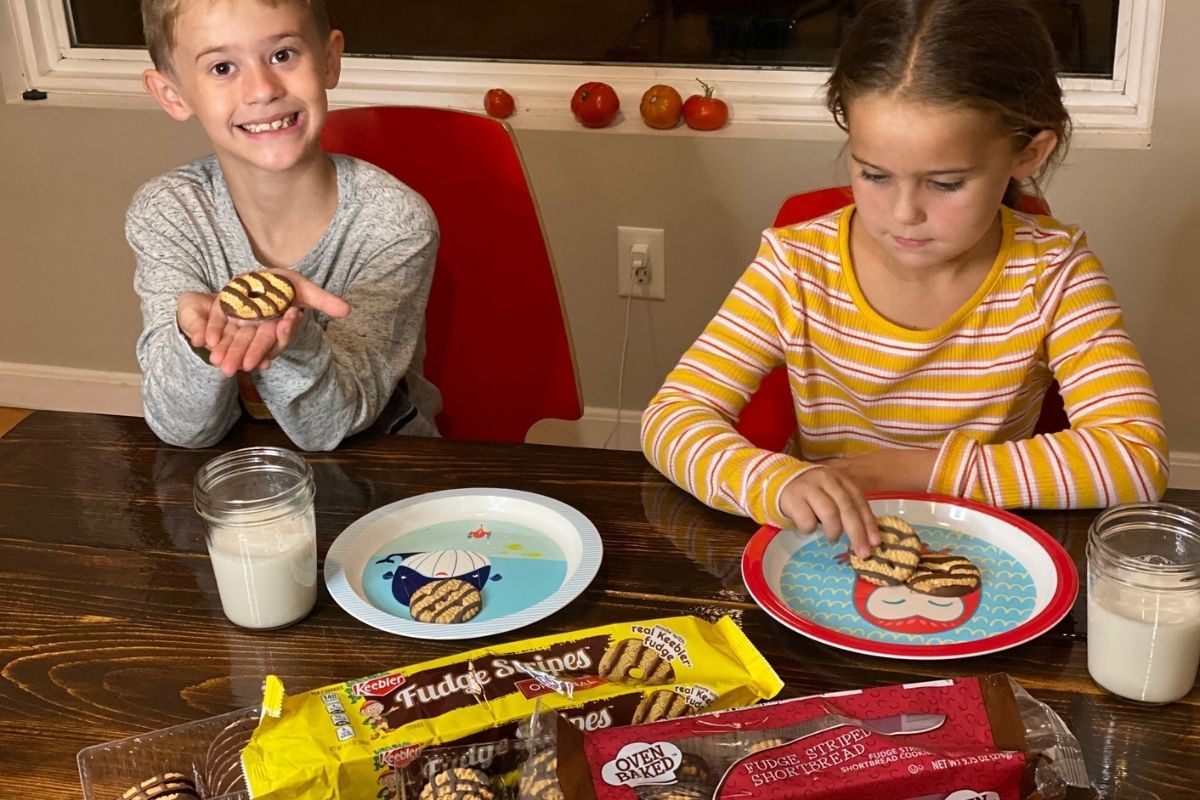 Two kids eating cookies at a table