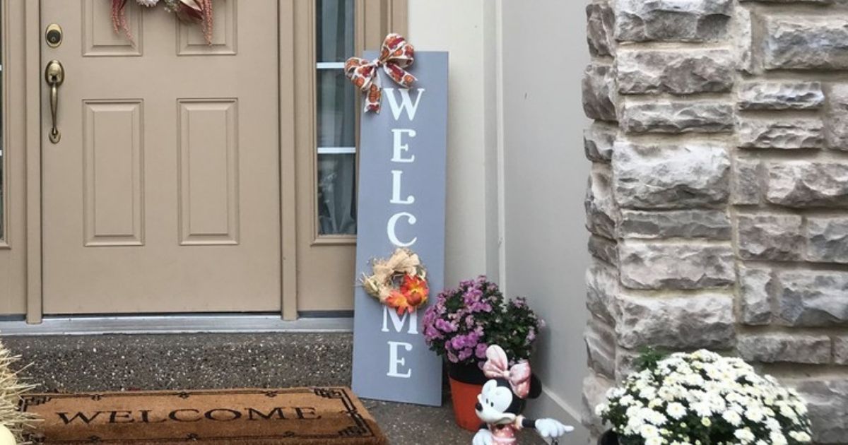 Gray and white WELonlineE sign with bows and wreath decor on front porch