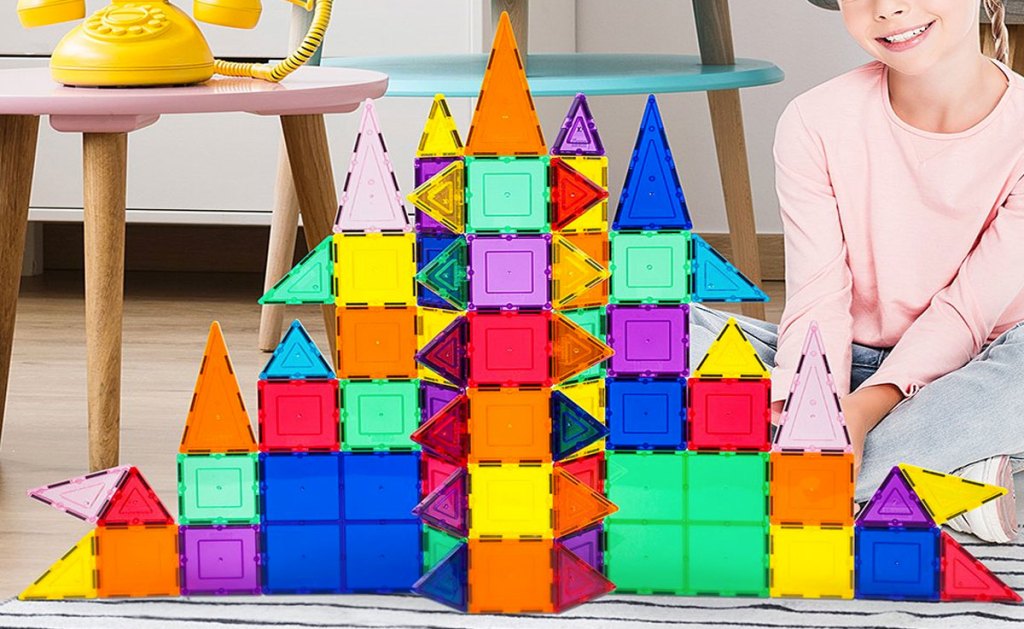 girl playing with rainbow magnetic tile set in shape of a castle