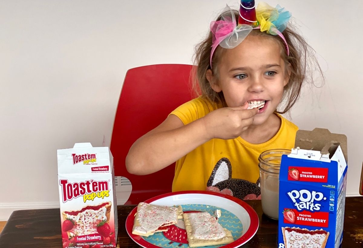 A little girl eating pop tarts at a table