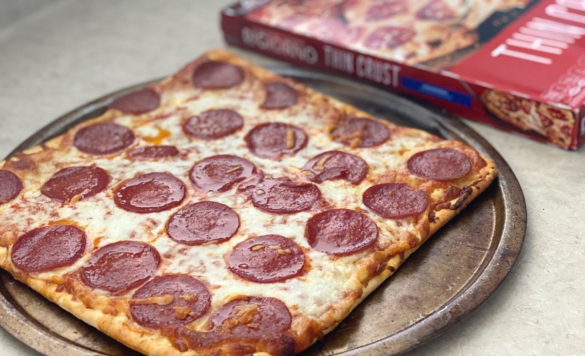 thin crust digiorno pizza on a pan next to the box on a counter