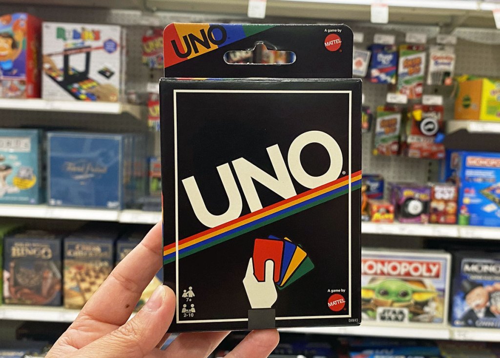 person holding up a retro themed UNO card game in toy aisle of target