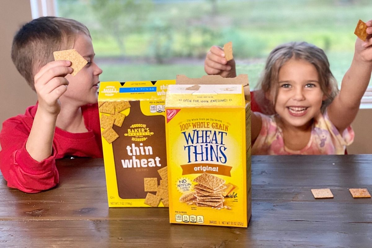 Two kids eating crackers at a table