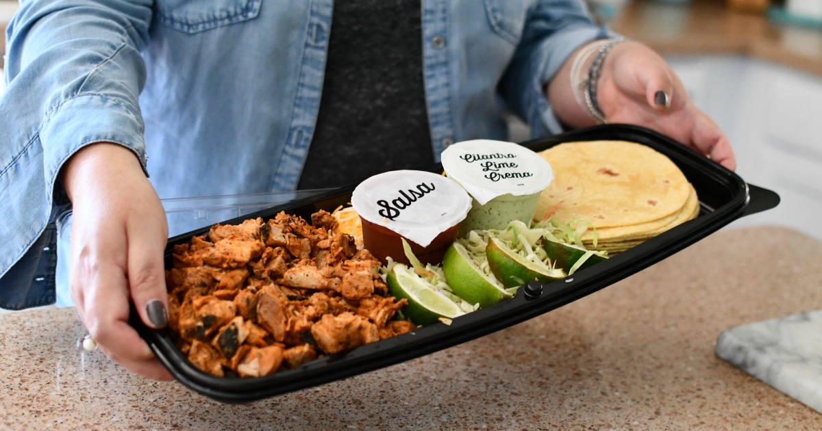 Woman holding a chicken taco kit from Costco for low effort meals. 