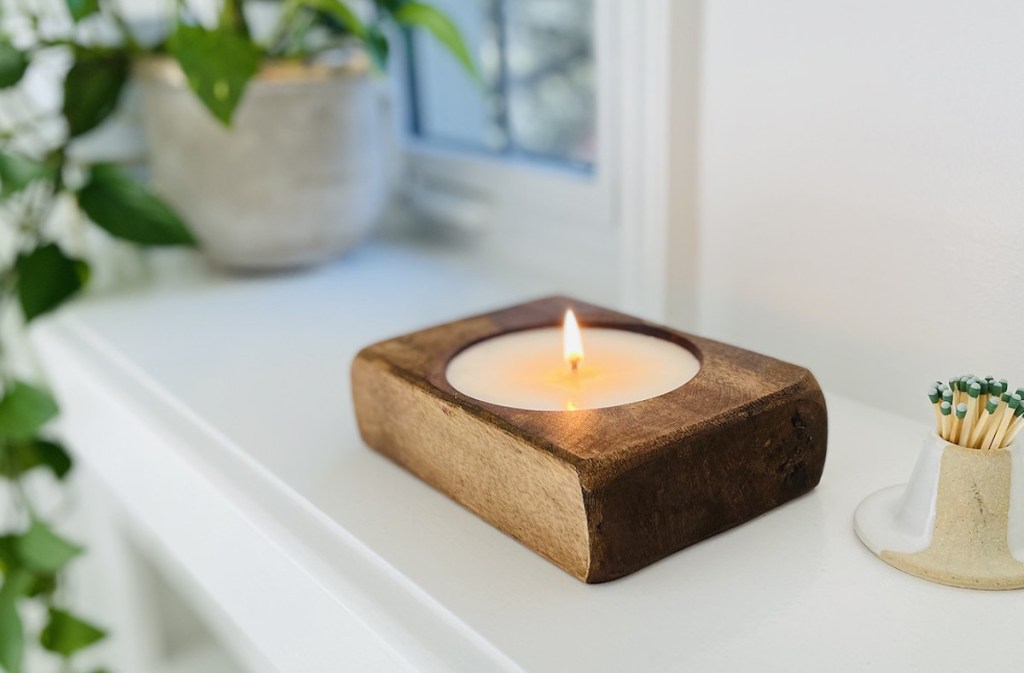 wood cheese hole candle next to matches and plant