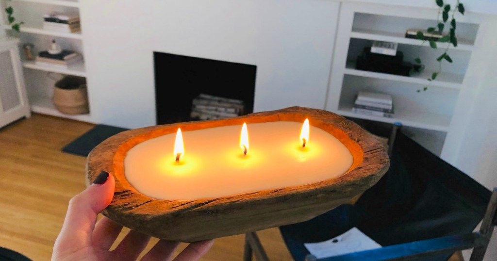 holding wood candle that's burning 