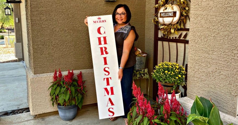 woman holding a merry christmas porch sign 