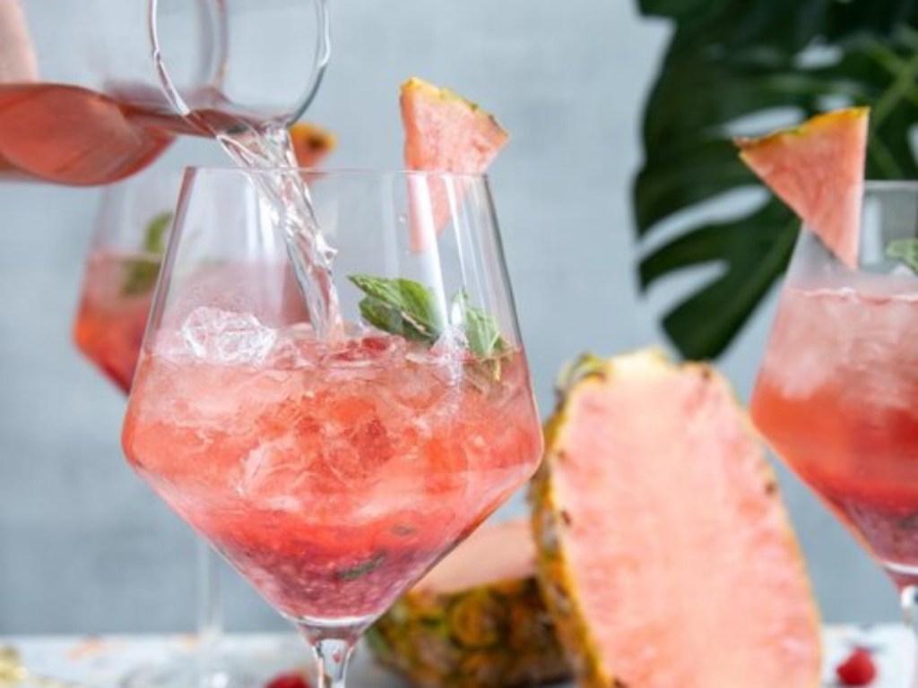 pouring pink drink into wine glass