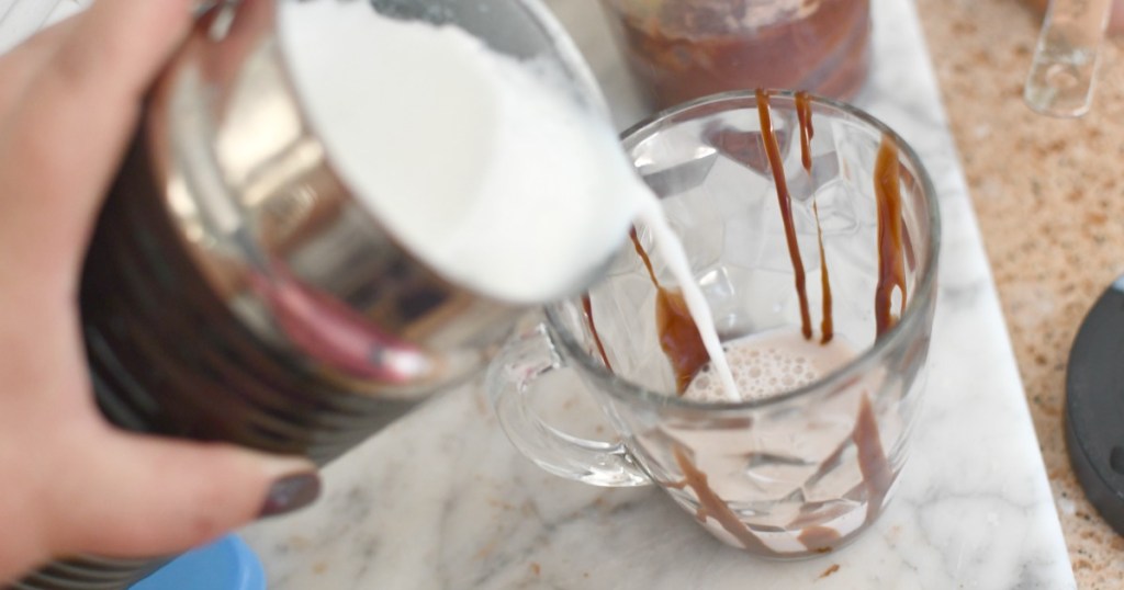 pouring hot frothed milk into coffee cup