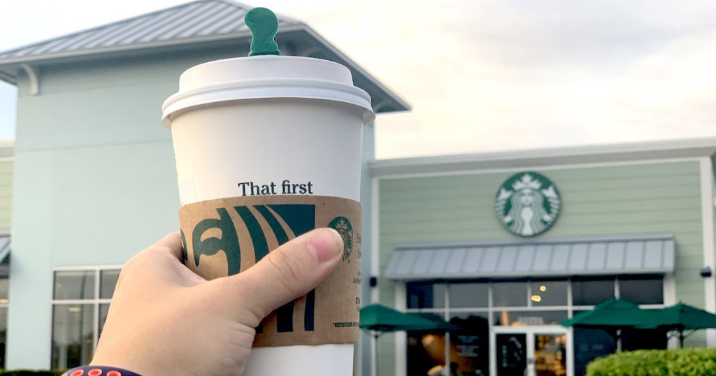 hand holding a cup of snickerdoodle latte in front of starbucks store