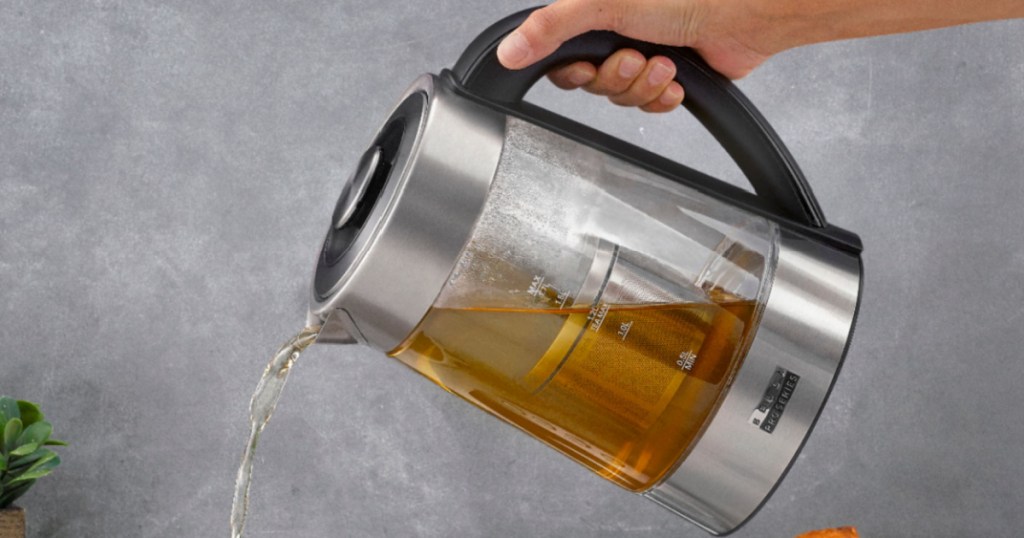 hand pouring tea from electric kettle