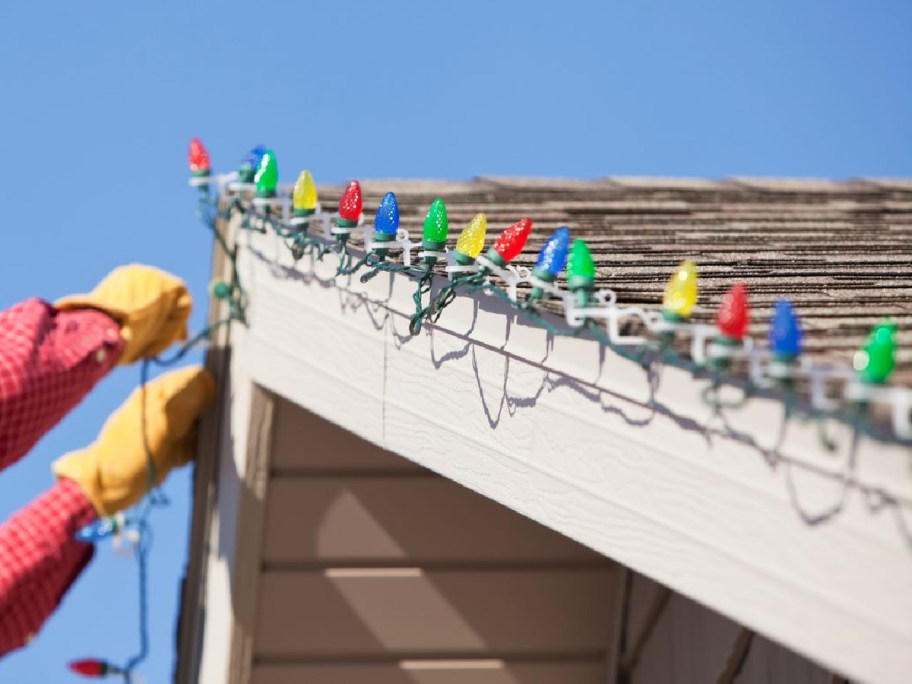 handyman hanging Christmas lights on home