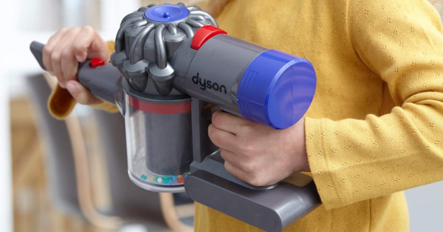 little girl holding a shortened Dyson kids stick vacuum