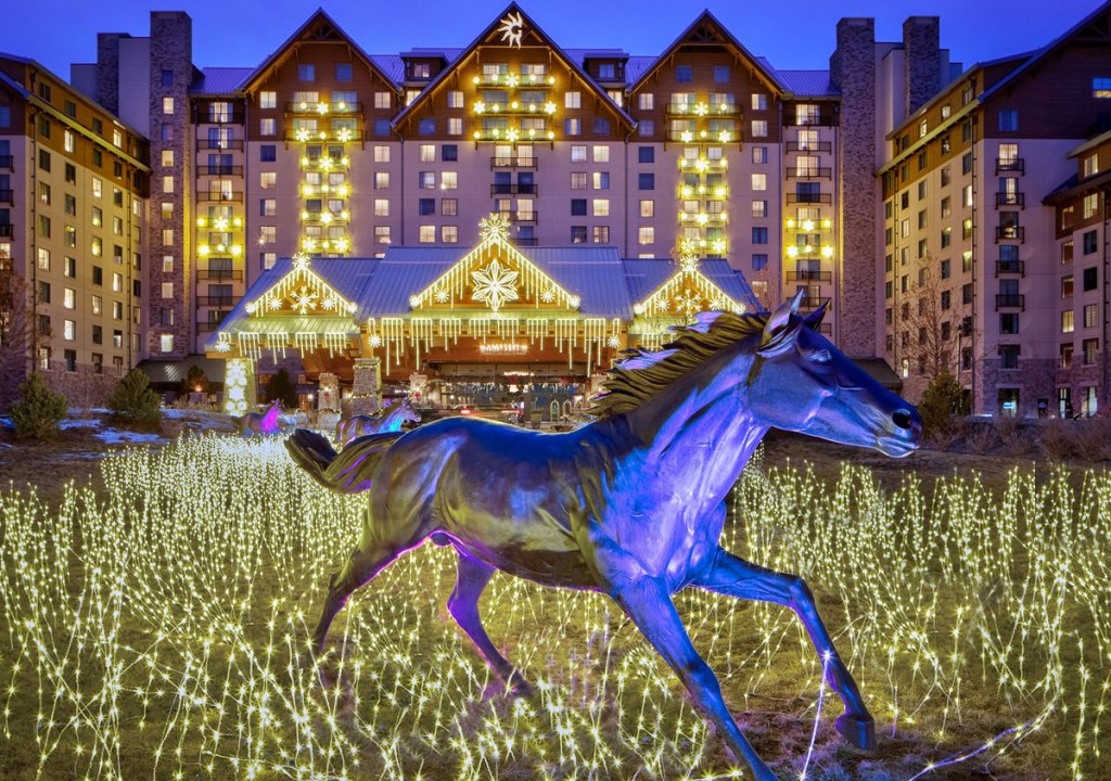 Gaylord Rockies hotel covered in white christmas lights with statue of horse in front of building