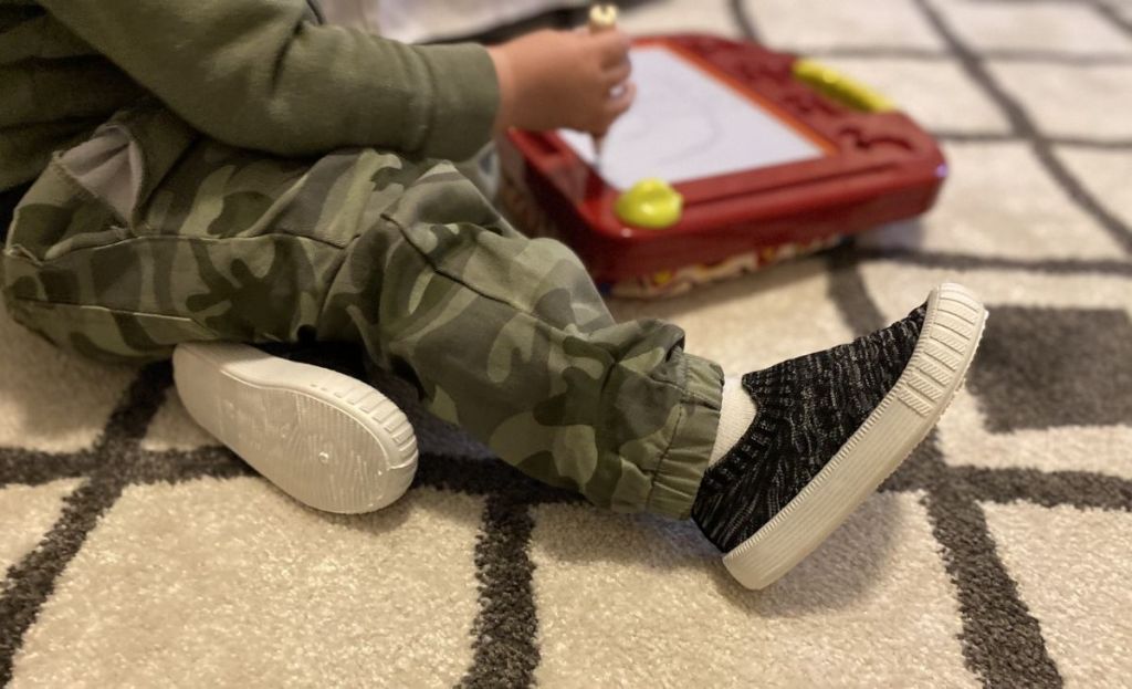 A toddler playing with an etch-a-sketch on the floor