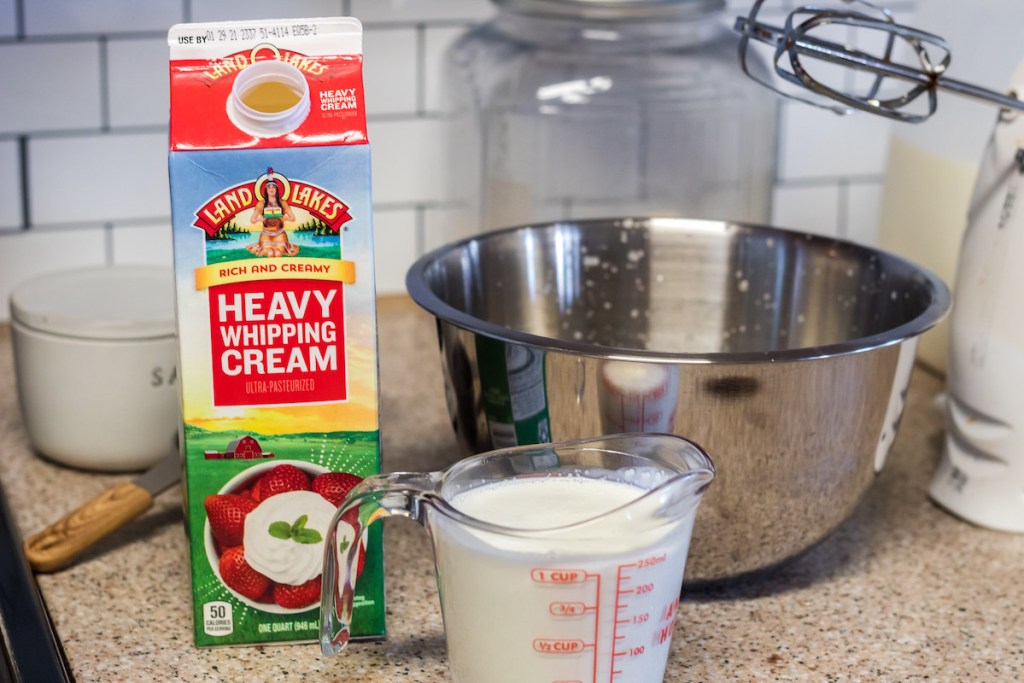 stainless steel bowl with heavy cream and measuring tools