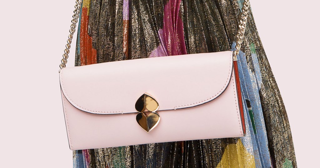 woman in a multi-color dress with a light pink crossbody bag with gold double heart closure and gold chain strap