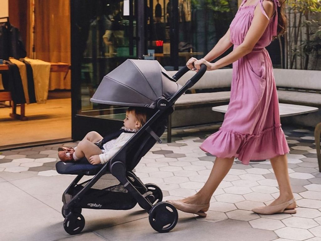 woman in pink dress pushing black stroller