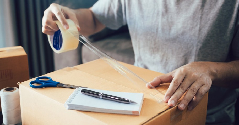 person putting tape on a shipping box in order to make christmas shipping deadlines for 2024