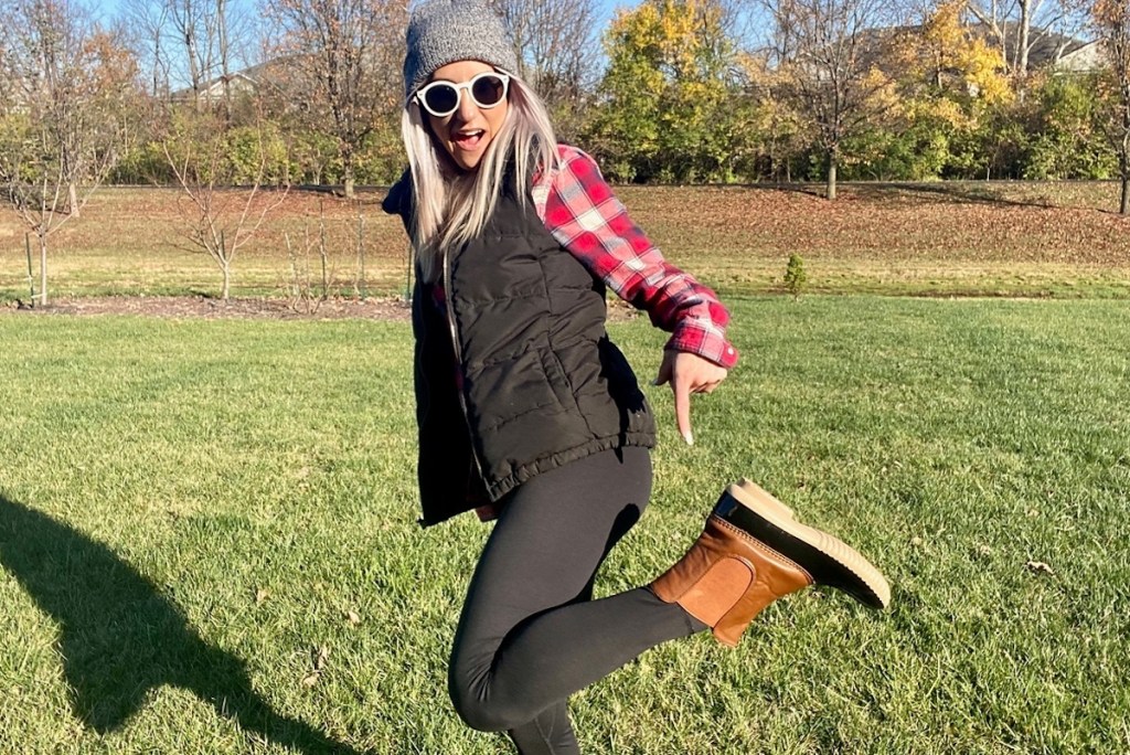 woman pointing to duck boots standing in grass