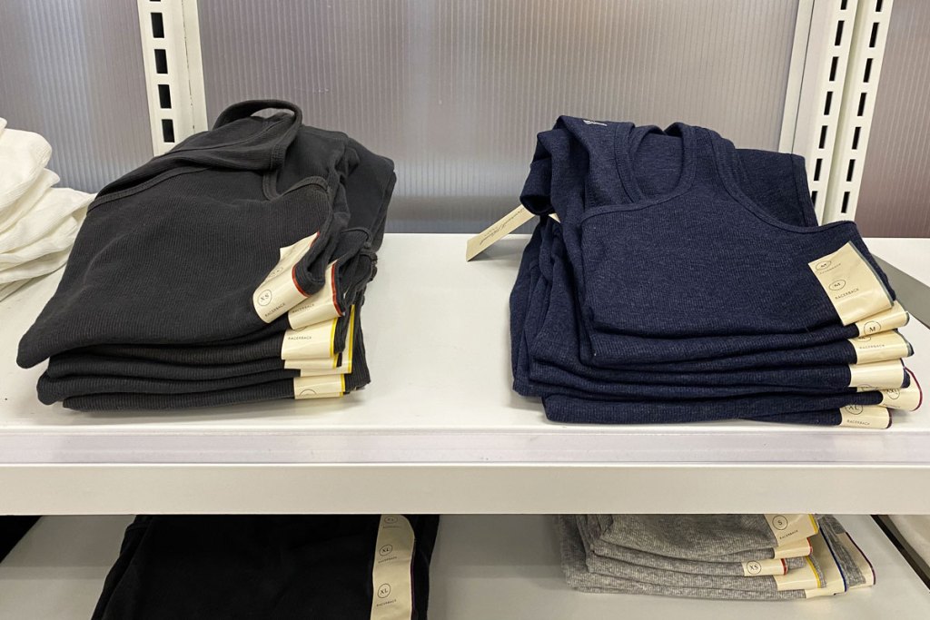 two piles of black and navy blue women's basic tank tops folded on white display shelf at target