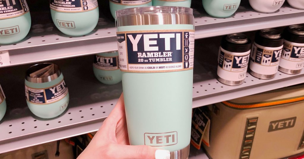 woman with white finger nails holding up a light blue yeti rambler mug