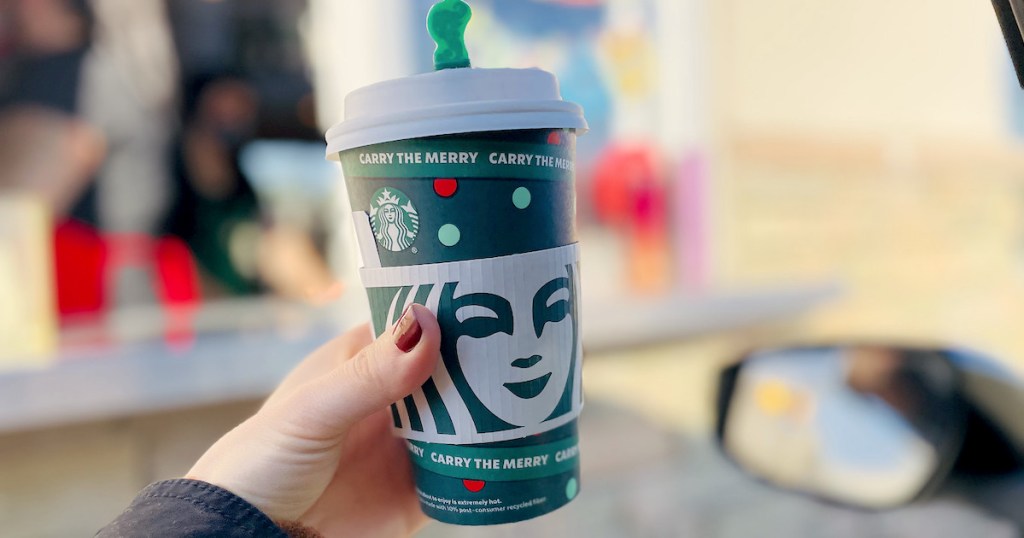 hand holding holiday Starbucks cup in drive thru