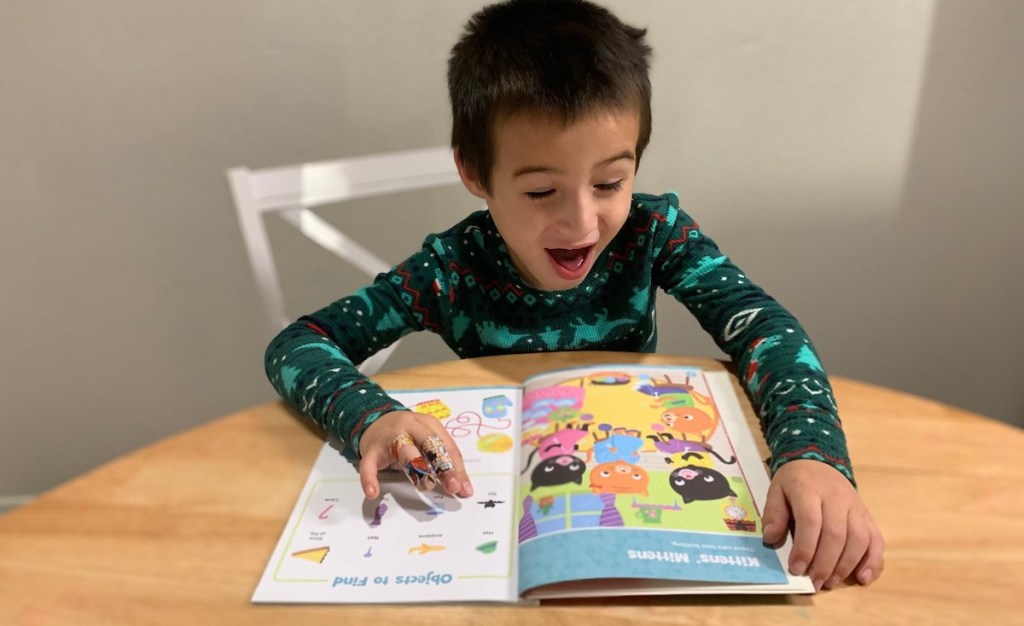 boy laughing looking at book on table