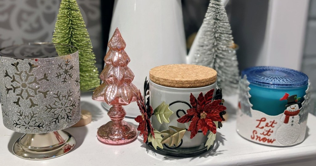 3 candles on white shelf with christmas decor