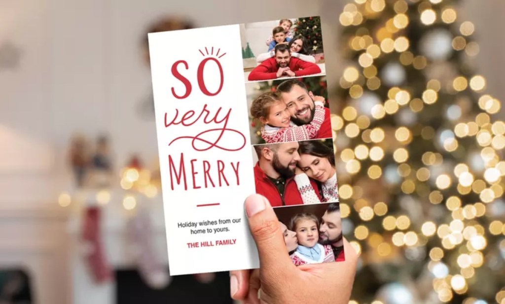 holding a photo card in front of a Christmas tree