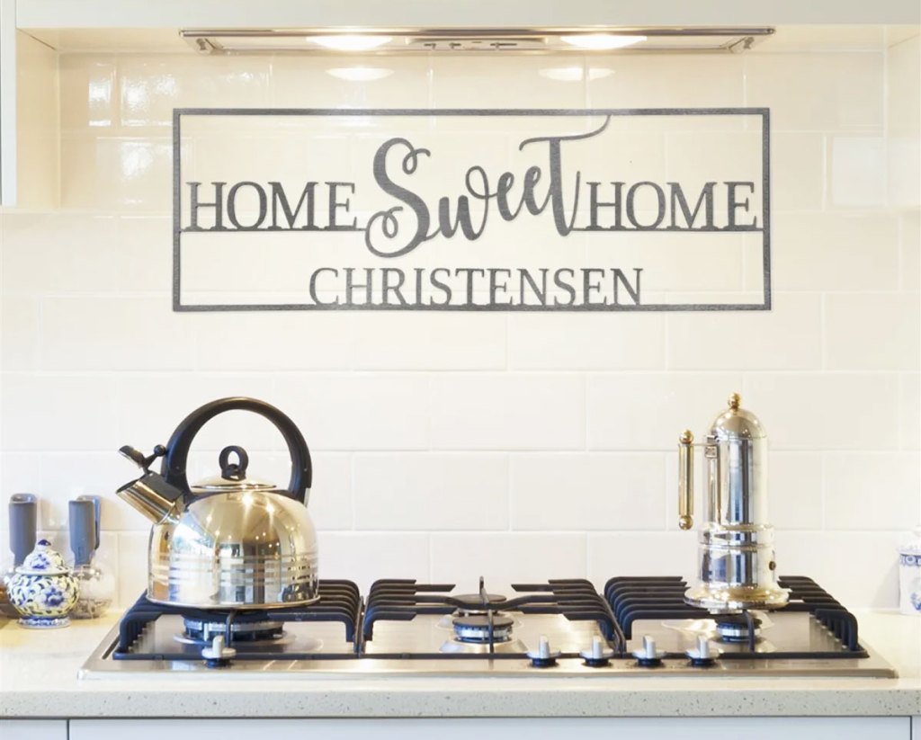 metal home sweet home sign with last name on it above a stove in kitchen