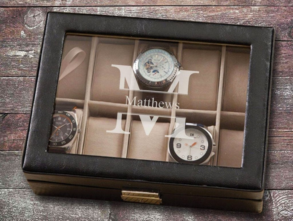 black leather watch box with glass top monogrammed with large M and has three watches inside