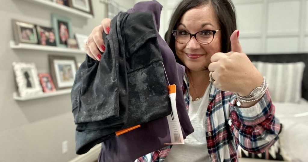 woman holding two paors of leggings giving thumbs up