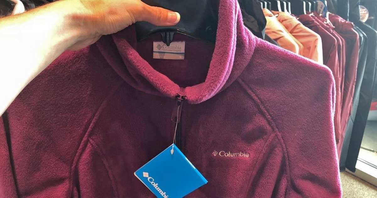 person holding up purple columbia jacket on hanger