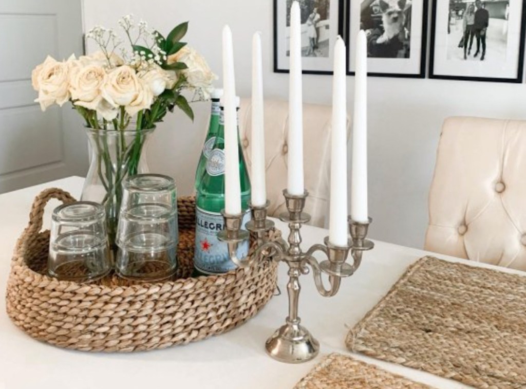 woven tray on table with glasses flowers and bottle of water