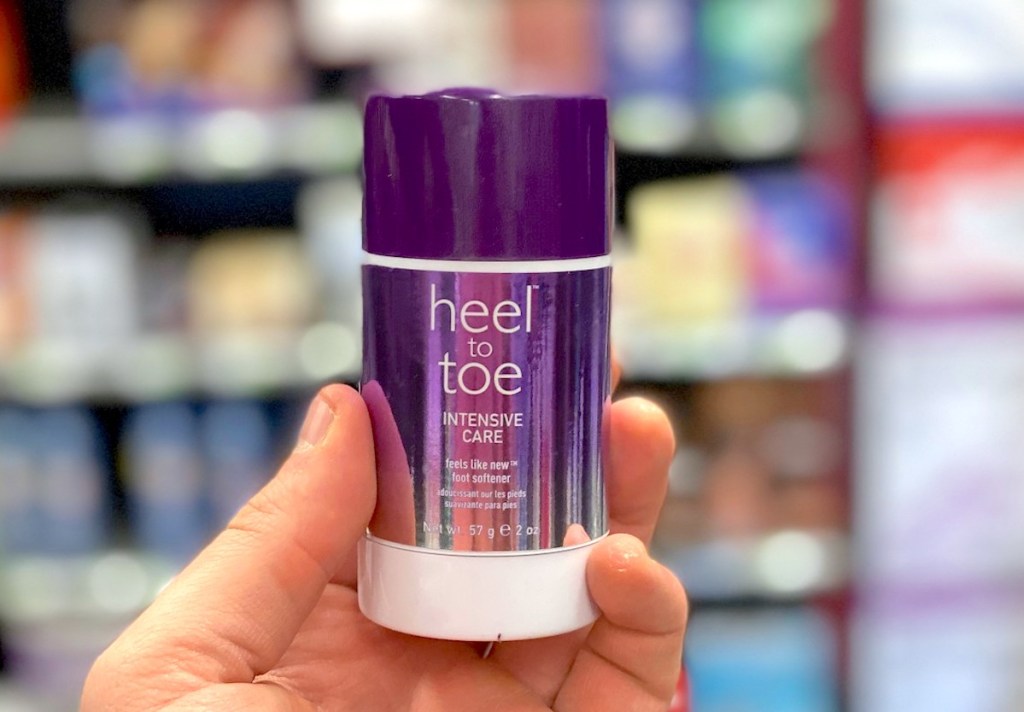 hand holding a purple stick of foot cream