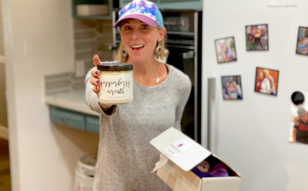 woman holding up white candle from subscription box