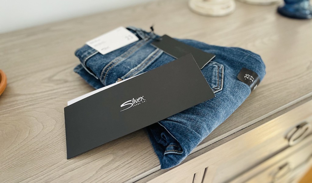 pair of silver jeans folded on top of dresser