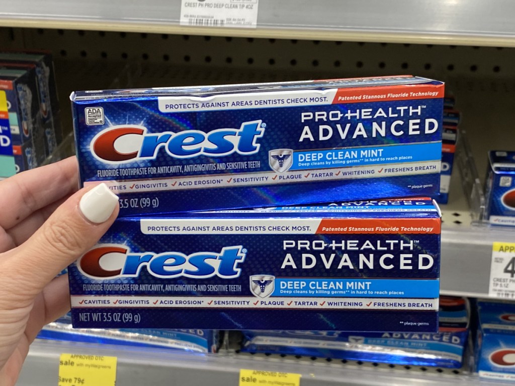 woman's hand holding two boxes of toothpaste in store