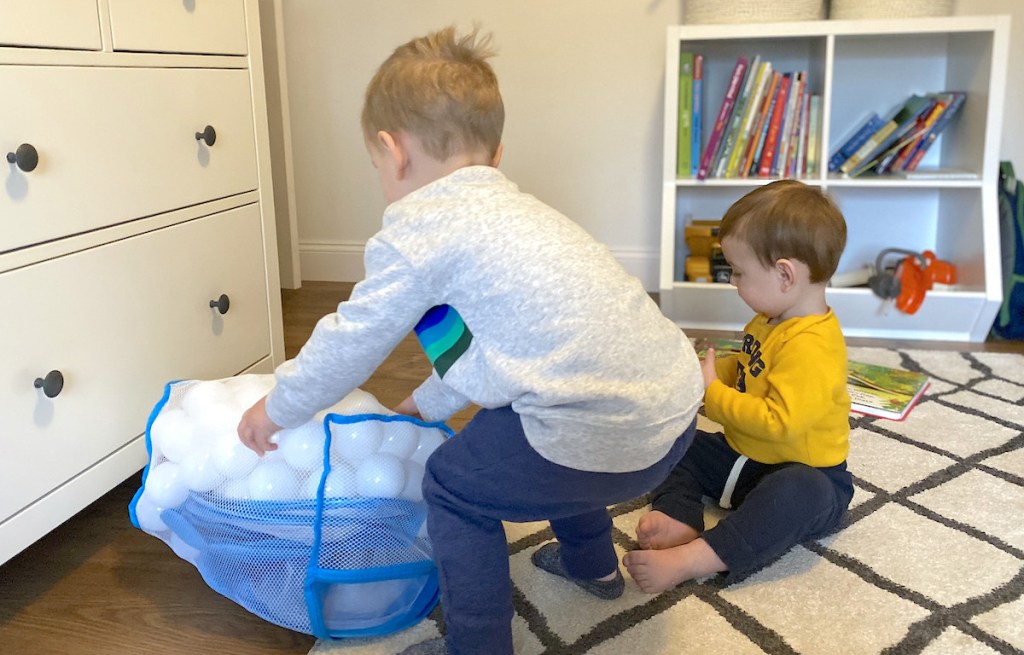 two little boys playing on rug with white plastic toy balls