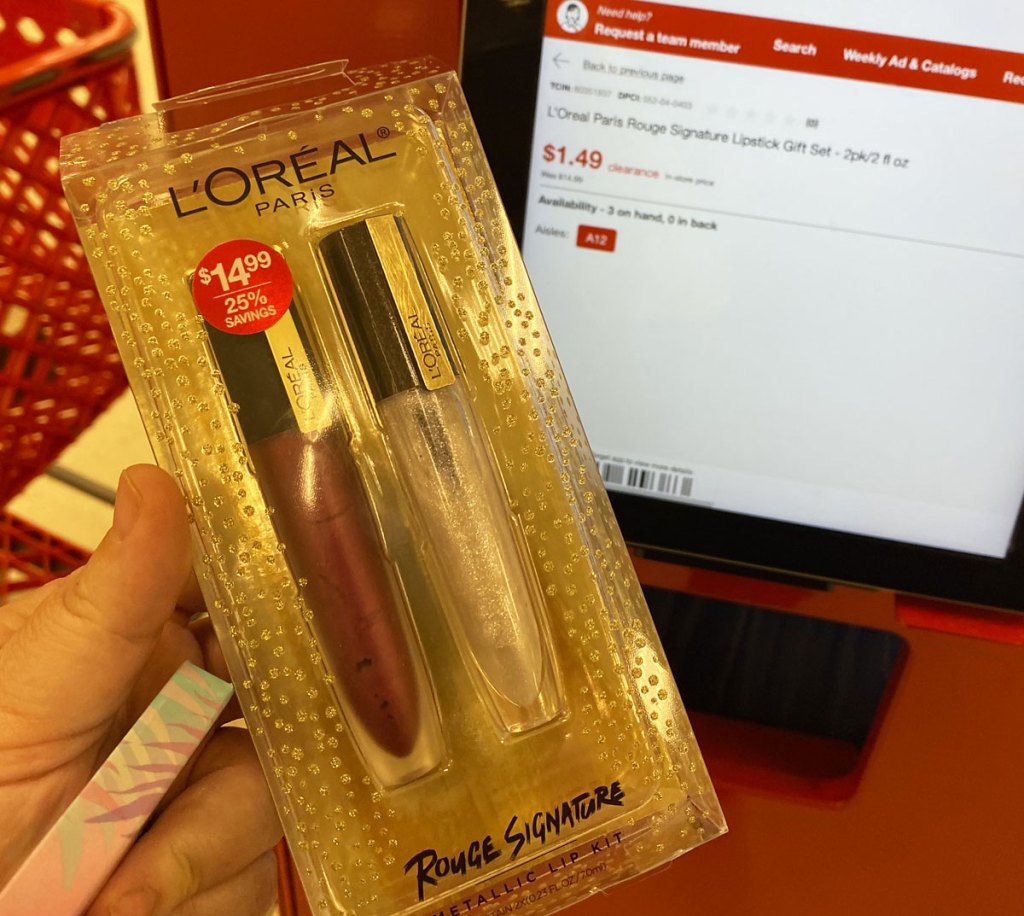 person holding up a 2-pack of loreal lip gloss at a target price scanner