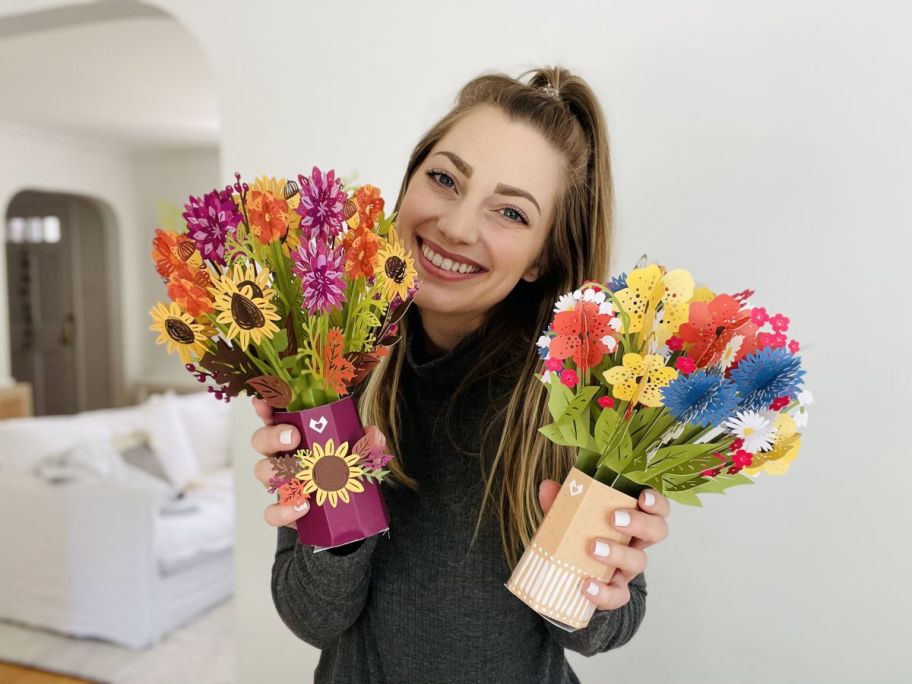 woman holding two paper flower bouquets