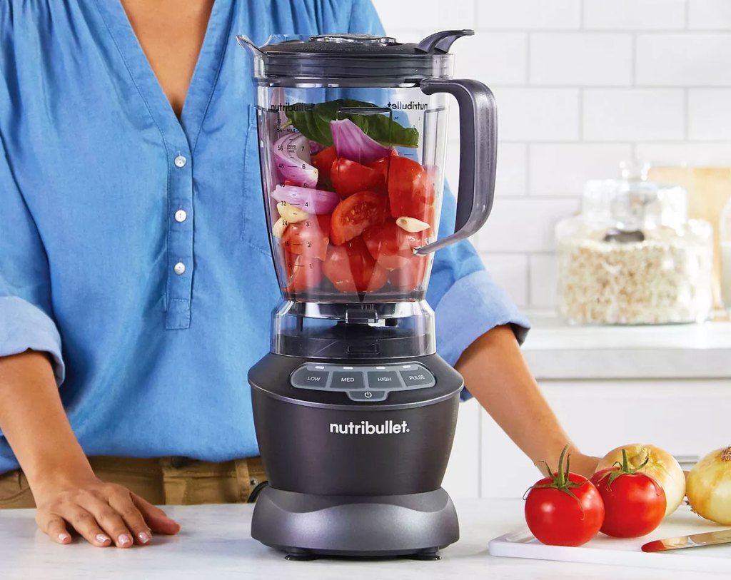 woman in blue shirt using a grey nutribullet blender to make salsa