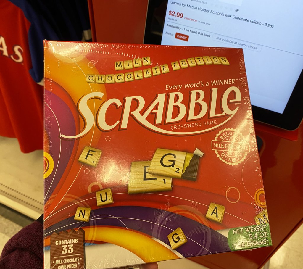 person holding up scrabble holiday edition game at target price scanner