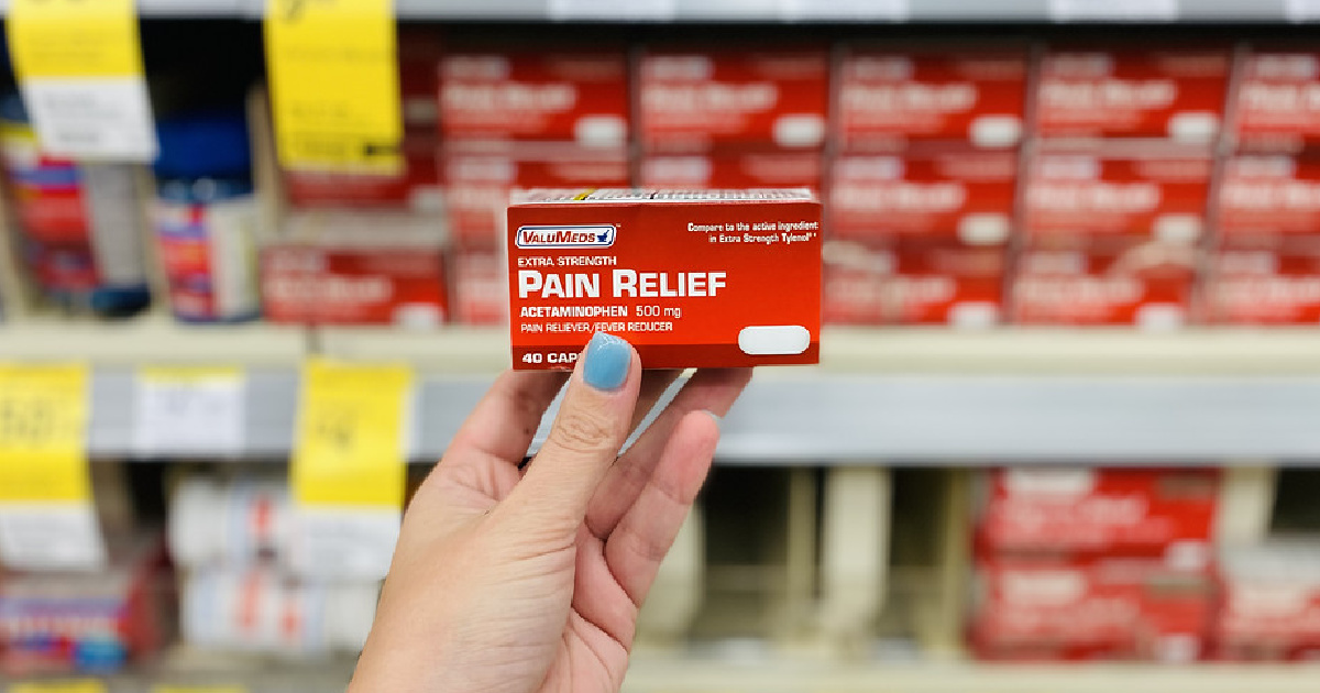 hand holding a box of pain reliever in front of a store display