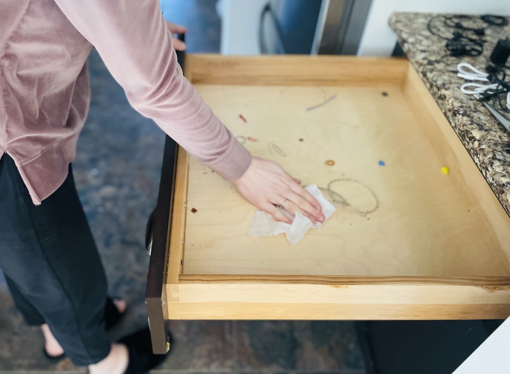 hand wiping down inside of dirty junk drawer