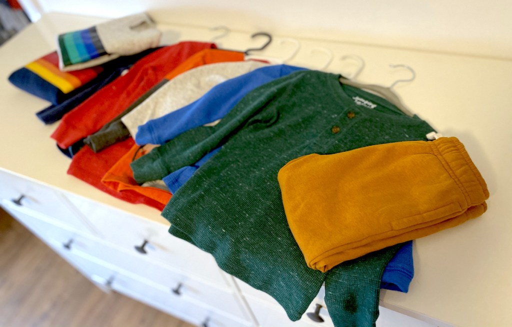 pile of colorful kids clothes on top of white dresser