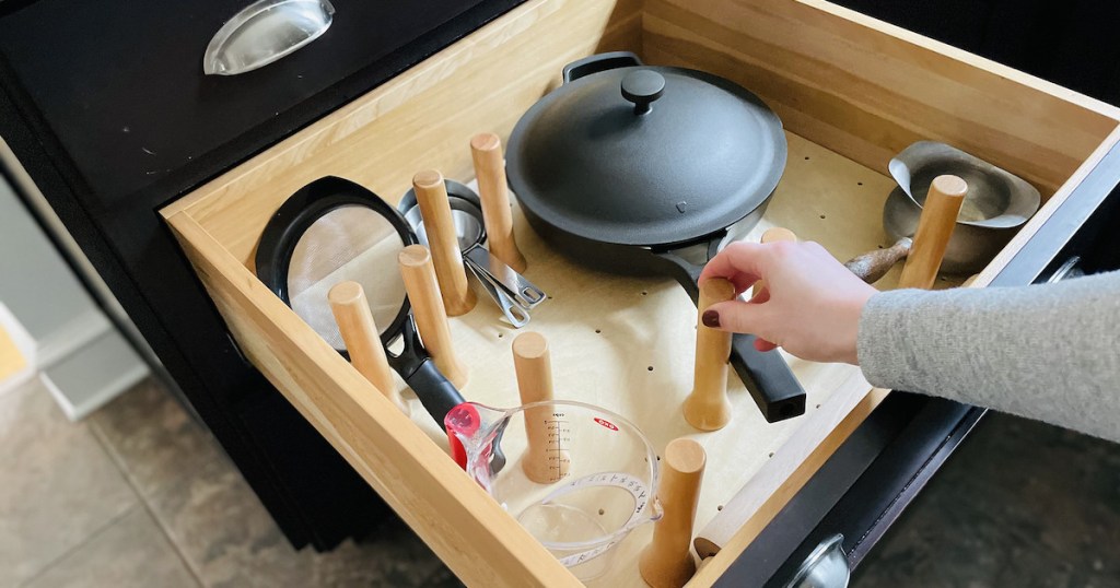 hand holding peg on wooden kitchen drawer peg board organizer