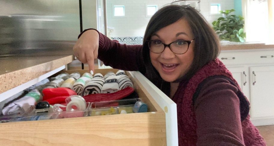 woman pointing inside organized junk drawer